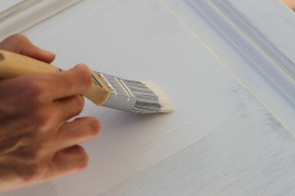 A person begins work on glazing a cabinet door.