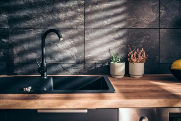A dark slate-colored sink is set into a butcherblock countertop.